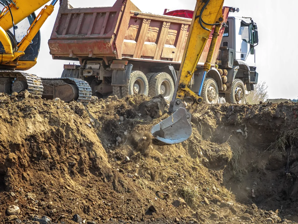 Escavadeira e caminhão basculante em operação de terraplenagem